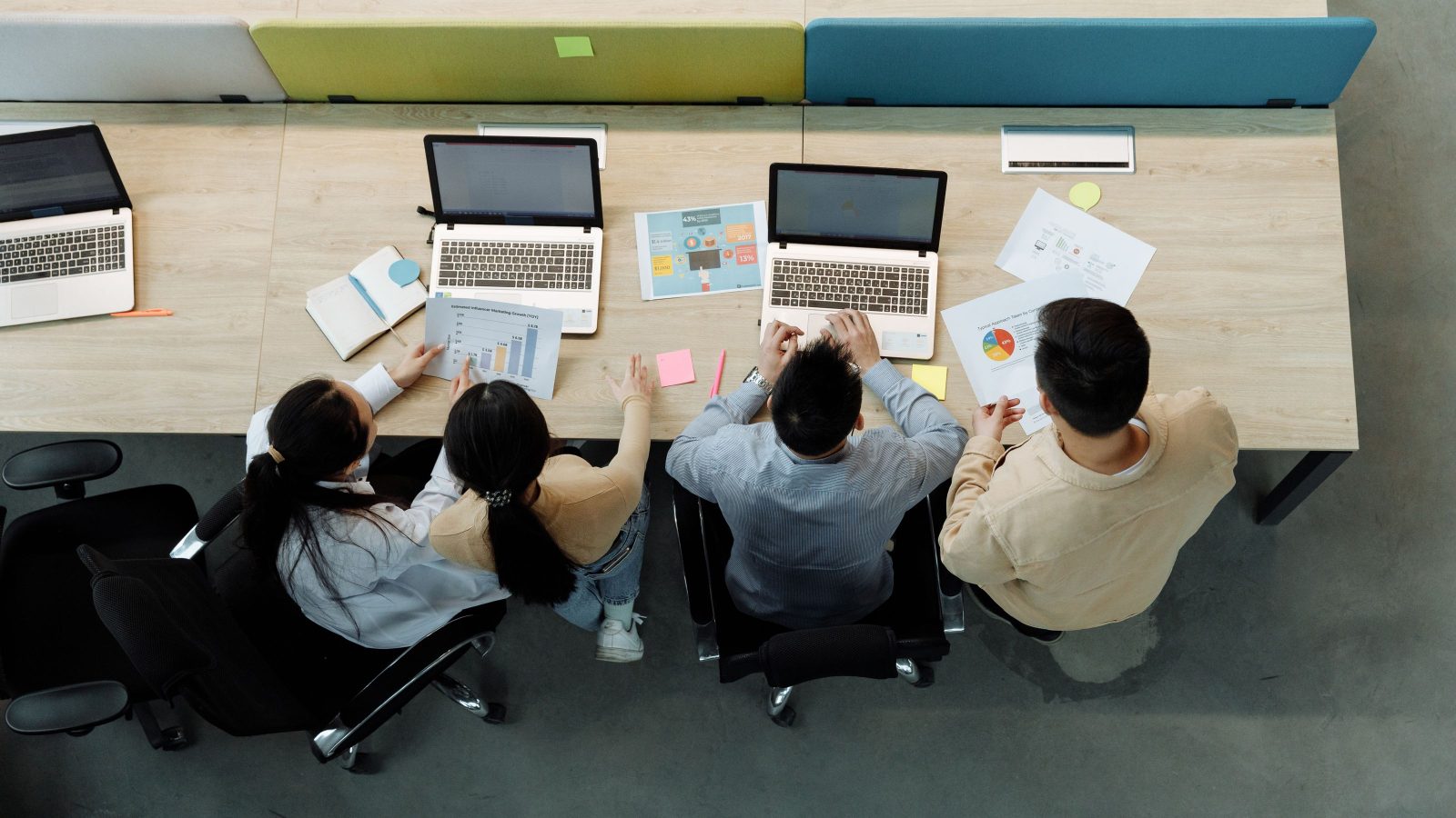 Overhead view of a team coordinating across several desks.