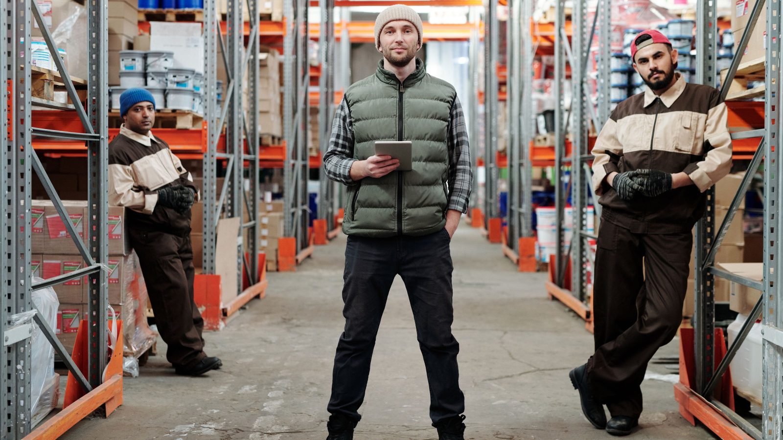 Two workers checking stock along a warehouse aisle.