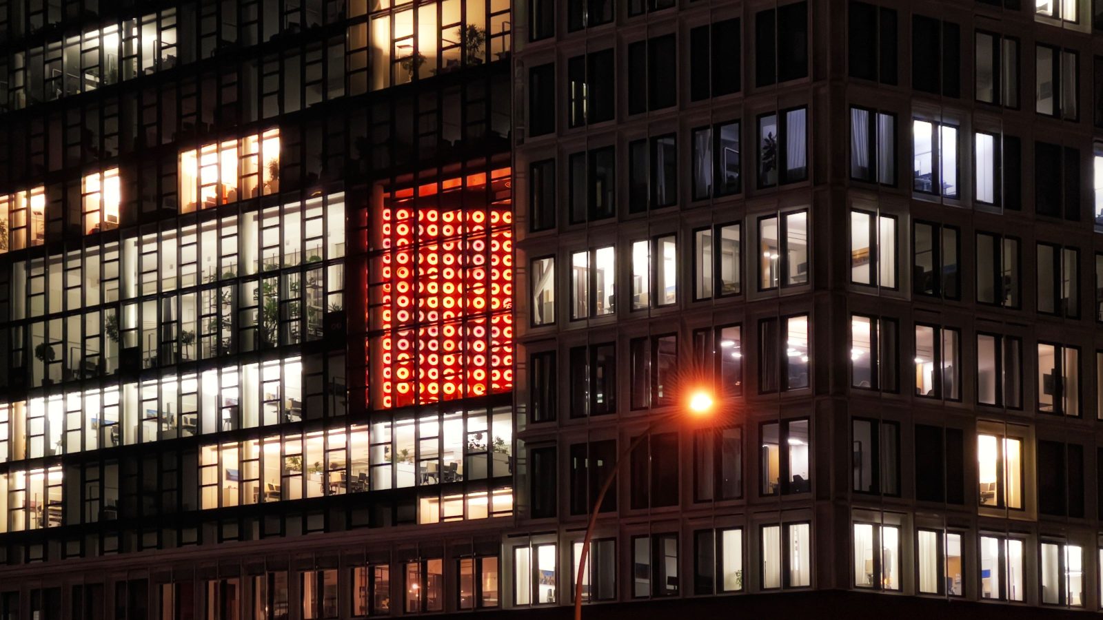 Office building lit from within during the evening as conditions outside change.